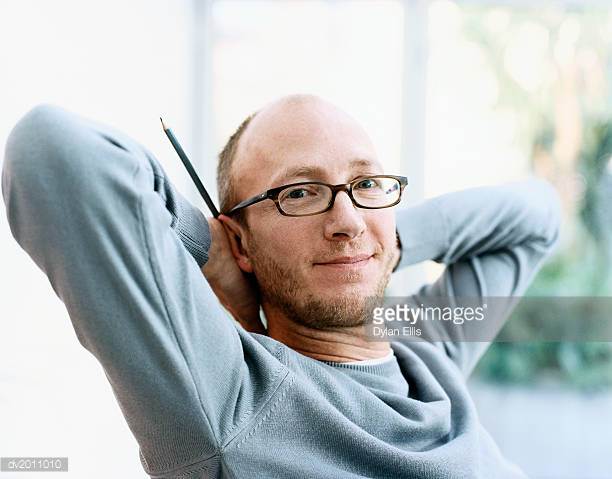 portrait-of-a-man-with-his-hands-behind-his-head-holding-a-pencil-picture-iddv2011010?s=612x612.jpg